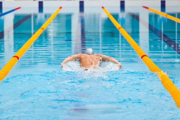 Dynamic and fit swimmer in cap breathing performing the butterfly stroke — Stock Photo, Image