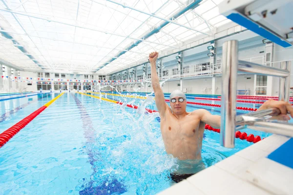 Nadador deportivo ganando. Hombre nadando celebrando el éxito de la victoria sonriendo feliz en la piscina usando gafas de baño y gorra gris . —  Fotos de Stock