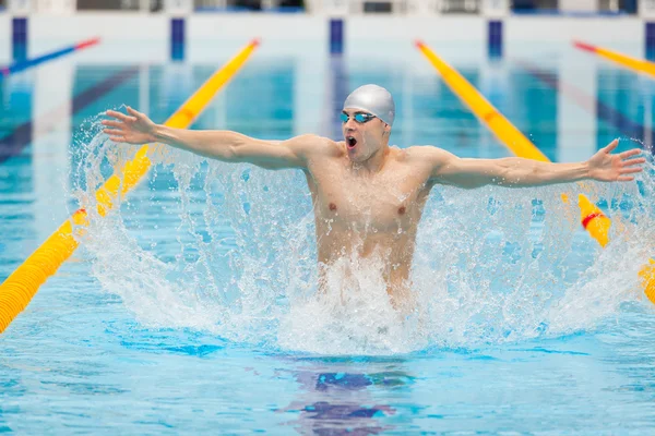 Dynamic and fit swimmer in cap breathing performing jumping out the water, concept of victory, freedom, happiness, healthy lifestyle — Stock Photo, Image