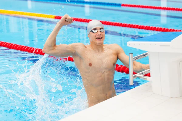 Nadador desportivo a ganhar. Homem nadando torcendo celebrando o sucesso da vitória sorrindo feliz na piscina usando óculos de natação e boné cinza . — Fotografia de Stock