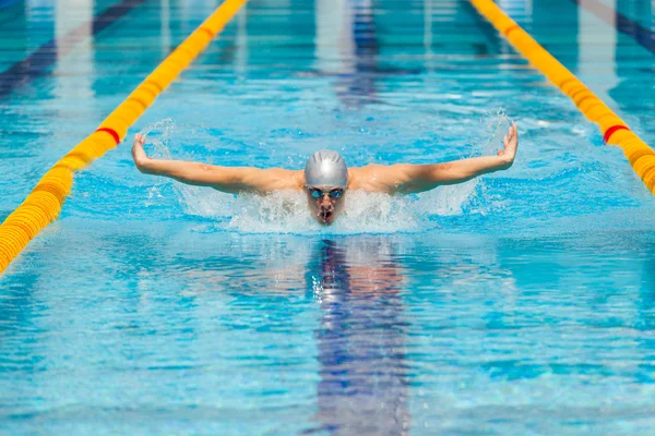 Dynamic and fit swimmer in cap breathing performing the butterfly stroke — Stock Photo, Image