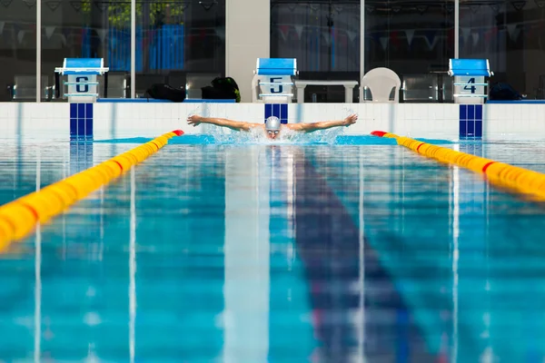 Dynamic and fit swimmer in cap breathing performing the butterfly stroke — Stock Photo, Image