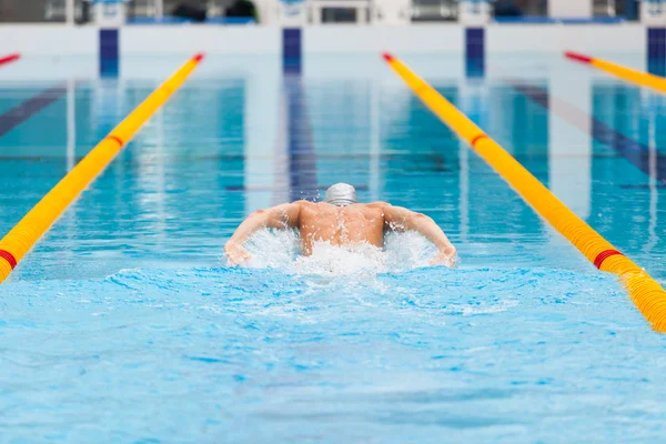 Dynamic and fit swimmer in cap breathing performing the butterfly stroke — Stock Photo, Image