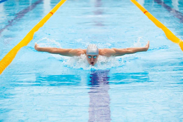 Dynamic and fit swimmer in cap breathing performing the butterfly stroke — Stock Photo, Image