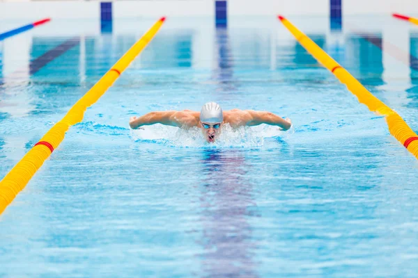 Dynamic and fit swimmer in cap breathing performing the butterfly stroke — Stock Photo, Image