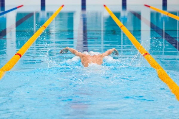 Dynamic and fit swimmer in cap breathing performing the butterfly stroke — Stock Photo, Image