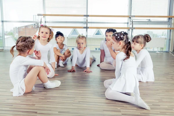 Grupo de sete pequenas bailarinas sentadas no chão. Eles são bons amigos e artistas de dança incríveis — Fotografia de Stock