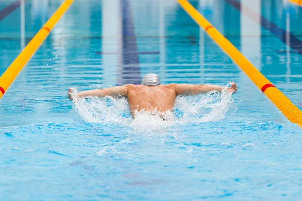 Nuotatore dinamico e in forma in cap respirando eseguendo il colpo della farfalla — Foto Stock