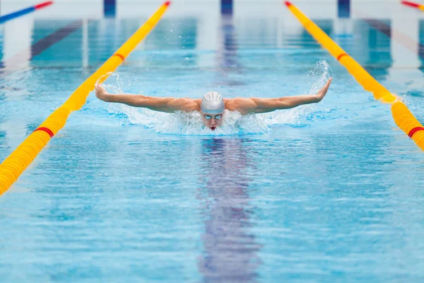 Dynamic and fit swimmer in cap breathing performing the butterfly stroke — Stock Photo, Image