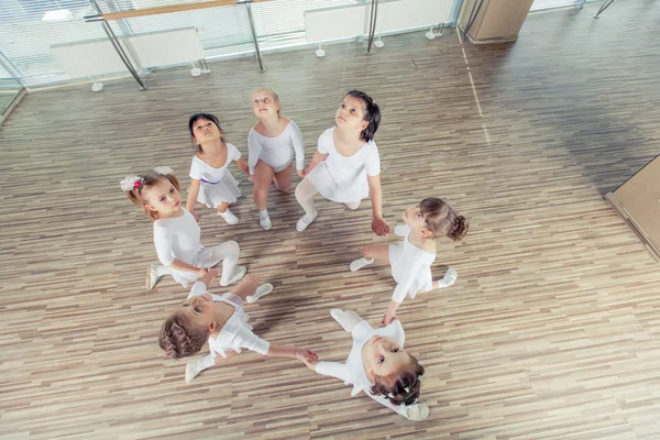 Grupp av sju små ballerinor sitter på golvet. De är god vän och fantastiska dans artister — Stockfoto