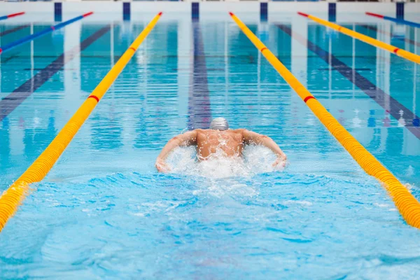 Dynamic and fit swimmer in cap breathing performing the butterfly stroke — Stock Photo, Image