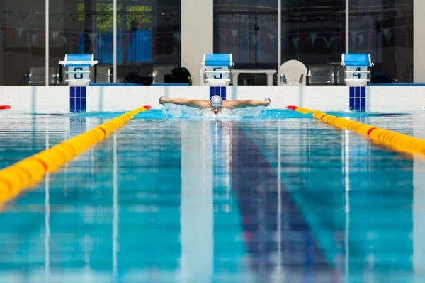 Dynamic and fit swimmer in cap breathing performing the butterfly stroke Stock Picture