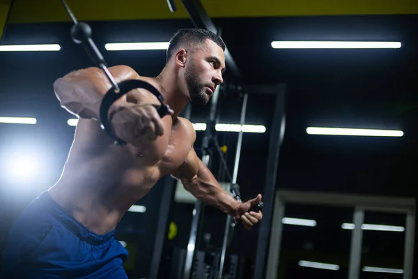 Side view portrait of a bodybuilder working on his chest muscles with cable crossover in a gym — Stock Photo, Image