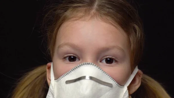 Концепция коронавируса и загрязнения воздуха. Маленькая девочка в маске для защиты. Коронавирус Ухана и симптомы эпидемии вируса. Смотрит в камеру. Поощряет чувство вины перед детьми — стоковое фото
