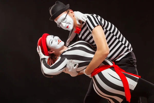 Retrato de dos artistas de mimo actuando, aislados sobre fondo negro. Hombre apoyando a su mujer mientras baila. Símbolo de pasión, baile en pareja, abrazo —  Fotos de Stock