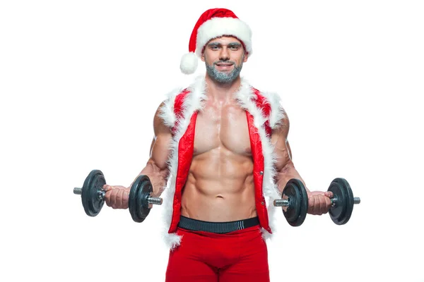 Sexy Santa Claus. Culturista joven guapo santa clausula sonrisa sostiene una mancuernas y muestra los cubos abdominales en la víspera de Año Nuevo y Navidad invierno vacaciones fondo blanco. — Foto de Stock