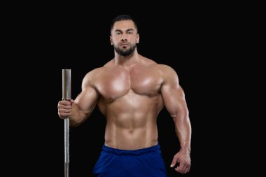 Genç seksi sporcu, bir eliyle siyah arka planda izole bir halterle ayakta duruyor.