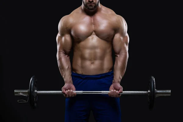 Guapo hombre de fitness está de pie con una pesada barra de pesas listo para entrenar aislado sobre fondo negro — Foto de Stock