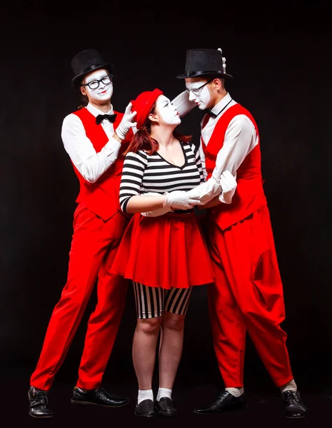 Porträtt av tre mimare, isolerad på svart bakgrund. En man förenar huvudet på en man och en kvinna i en kyss. Symbol för upphandling, Amor, äktenskapsmäklare — Stockfoto
