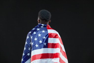 Siyah arka planda izole edilmiş Amerikan bayrağı giyen bir adam. Vatanseverlik kavramı, vatan sevgisi, ulusal sembol.