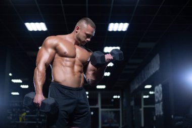 Spor salonunda ağırlık kaldıran genç bir vücut geliştirici..