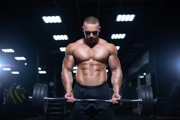 Gespierde sexy bodybuilder is het doen van gewicht tillen van de lange halter in de sportschool — Stockfoto