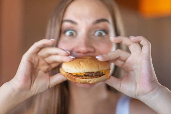 Gros plan de belle jeune brune affamée est sur le point de mordre un délicieux hamburger. Concept de malbouffe et de restauration rapide — Photo