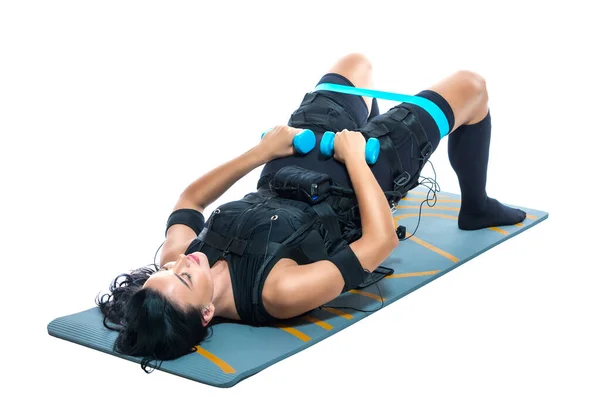 Une jeune femme sportive en costume EMS fait un exercice sur un tapis d'haltère sur un fond blanc isolé. Formation EMS. Stimulateur musculaire électrique. — Photo