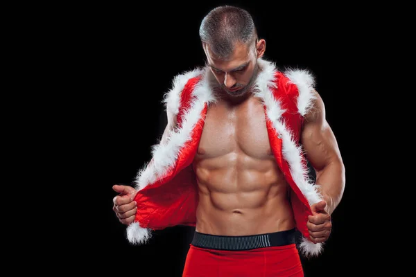 Pai Natal sexy. Jovem homem musculoso usando chapéu de Papai Noel demonstrar seus músculos. Isolado em fundo preto. — Fotografia de Stock