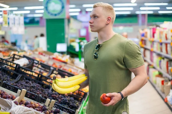 Jovem desportista está escolhendo frutas na mercearia. Conceito de nutrição saudável, dieta equilibrada, vitaminas — Fotografia de Stock