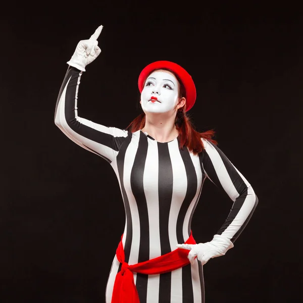 Portrait of female mime artist performing, isolated on black background. Woman in a striped dress is standing with raised hand. Symbol of attention, warning, nota bene — Stock Photo, Image