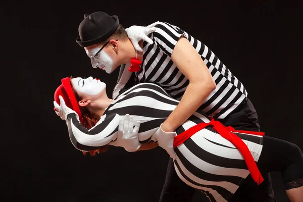 Retrato de dos artistas de mimo actuando, aislados sobre fondo negro. Hombre apoyando a su mujer mientras baila. Símbolo de pasión, baile en pareja, abrazo —  Fotos de Stock