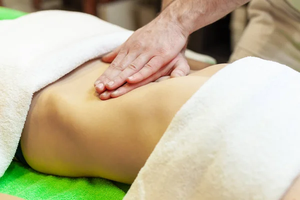 Sidovy av händer massera kvinnlig buk. Terapeut sätter tryck på magen. Kvinna som får massage på spa salong — Stockfoto