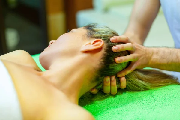 Relaxamento total. Mulher bonita deitada de costas, enquanto massagista profissional massageando a cabeça — Fotografia de Stock