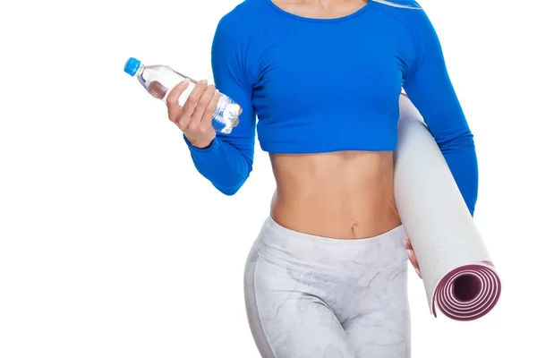 하얀 배경에 고립 된 손에 광천수 한 병과 매트를 들고 있는 매력적 인 스포츠 여성의 모습을 가까이서 찍은 사진 — 스톡 사진