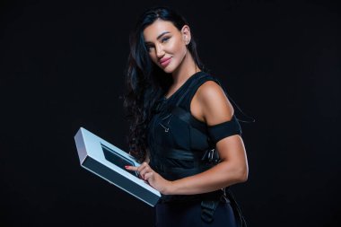 Tecrit edilmiş siyah bir arka planda EMS kıyafetli genç bir atletik kadın. Acil servis eğitimi. Elektro kas uyarma makinesi.