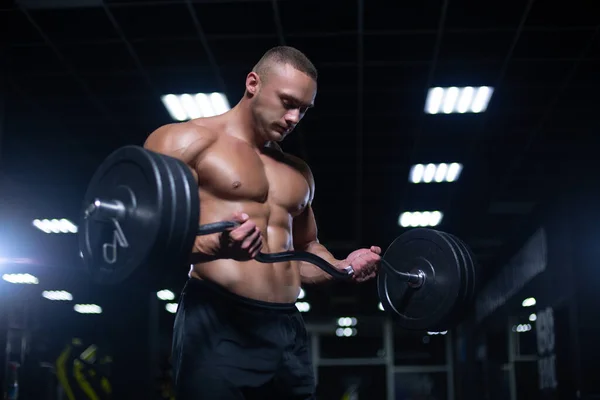 Muscular sexy culturista está haciendo ejercicio haciendo levantamiento de pesas de la barra en el gimnasio —  Fotos de Stock