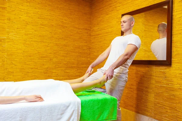 Masseur tire les jambes de la femme faisant massage thaïlandais traditionnel sur le corps de la femme dans le salon de spa. Concept de traitement beauté — Photo