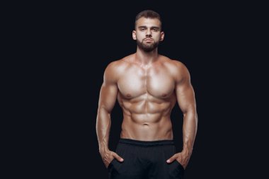 Siyah arka planda izole edilmiş kaslı ve formda genç vücut geliştirici fitness erkek modeli
