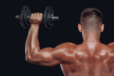Vücut geliştirenlerin arkasını kapatın güçlü kaslı kol siyah arkaplanda izole edilmiş bir halteri kaldırıyor.