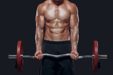 Güçlü vücut geliştirici kaslı kolları kapatın. Siyah arka planda izole edilmiş halteri kaldırın.