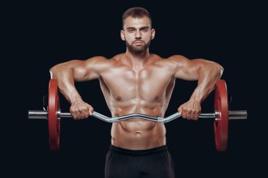 Siyah arka planda izole edilmiş halteri kaldıran güçlü bir vücut geliştiricinin ön görüntüsü.