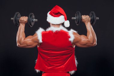 Seksi Noel Baba. Vücut geliştirici genç yakışıklı Noel Baba 'nın gülümseyişi yılbaşı arifesinde ve Noel tatilinin kara arka planında bir dambıl tutuyor. Arkadan manzara..