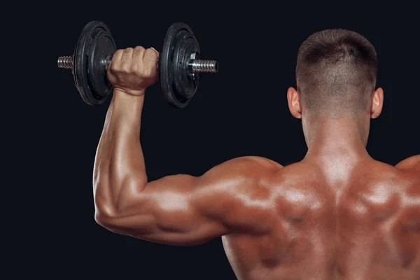 Close up back view on bodybuilders strong muscular arm lifting a dumbbell isolated on black background — Stock Photo, Image