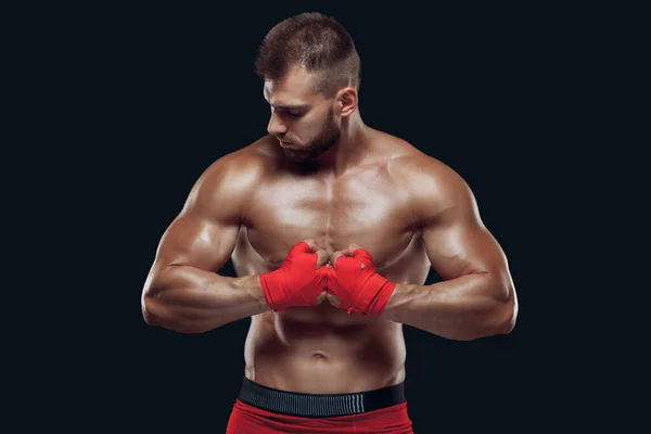 Front view of a sporty man in boxing gloves practicing fighting techniques isolated on black background — Stock Photo, Image