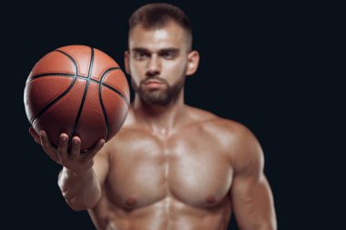 Siyah arka planda izole edilmiş kaslı bir erkek oyuncunun uzatılmış eliyle basketbol topunu kapat.