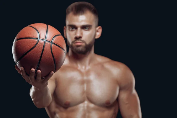 Gros plan d'un ballon de basket dans la main tendue d'un joueur masculin musclé isolé sur fond noir — Photo