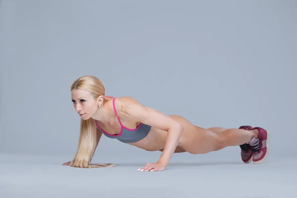 Сильна фітнес-дівчина виконує штовхання вправи ізольовані на сірому фоні — стокове фото