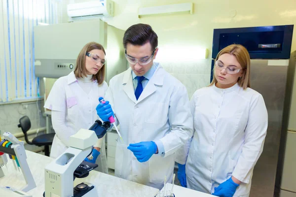 En grupp forskare bedriver forskning i ett vetenskapligt laboratorium med hjälp av avancerad teknik. COVID-19. COVID Coronavirus — Stockfoto