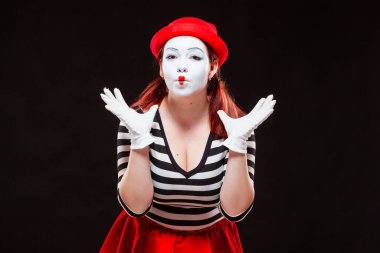 Siyah arka planda izole edilmiş kadın pandomim sanatçısının portresi. Çizgili elbiseli ve kırmızı etekli kadın ellerini kaldırmış hayret içinde bekliyor. Merakın, hayranlığın, tapınmanın sembolü.